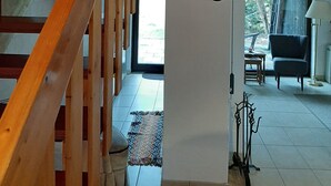 Una escalera con barandillas de madera que lleva a una plataforma. En la plataforma hay placas decorativas en la pared y un perchero.
