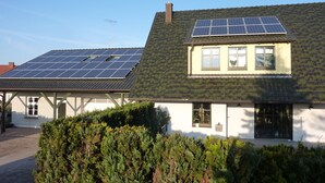 Une maison avec des panneaux solaires sur le toit et un petit jardin devant.