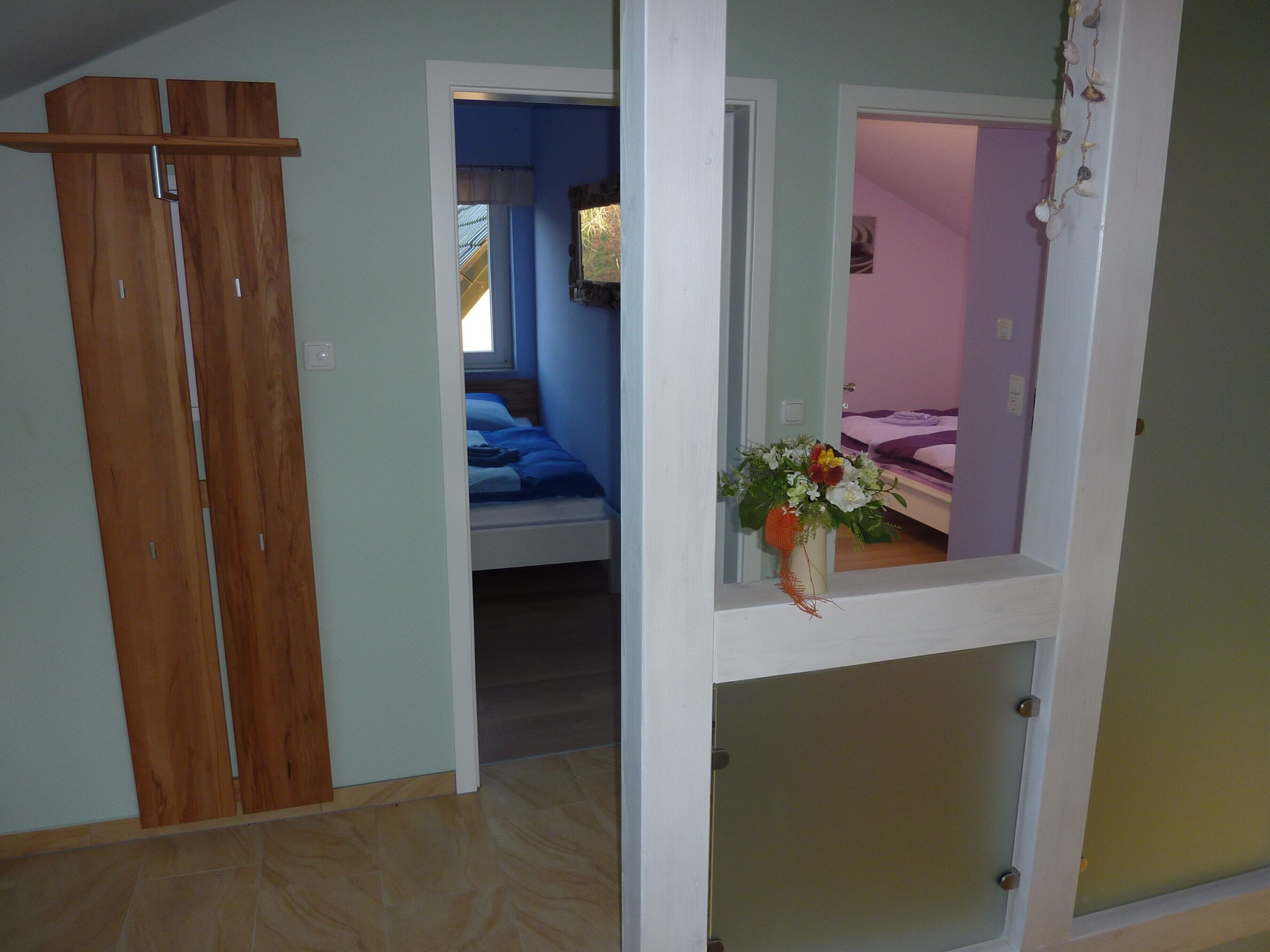A bedroom with a bed, a wooden wardrobe, and a window.