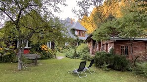 Una cabaña rústica con fachada de madera, rodeada por un jardín cuidado y un césped.