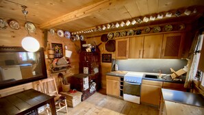 Un interior de madera con una zona de cocina que incluye estufa, lavamanos y varios utensilios de cocina.