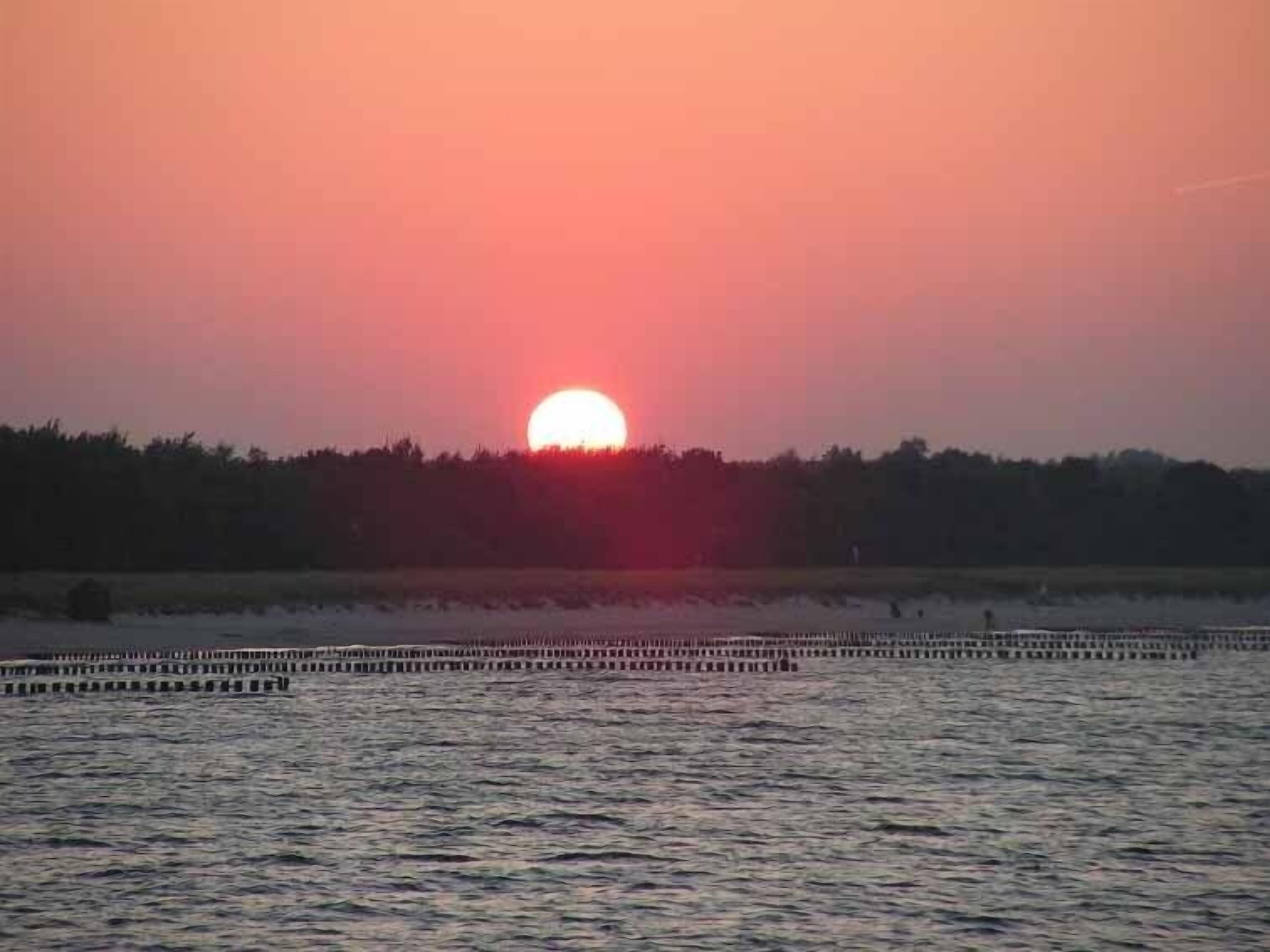 A sunset over a body of water with a dock extending into the water.