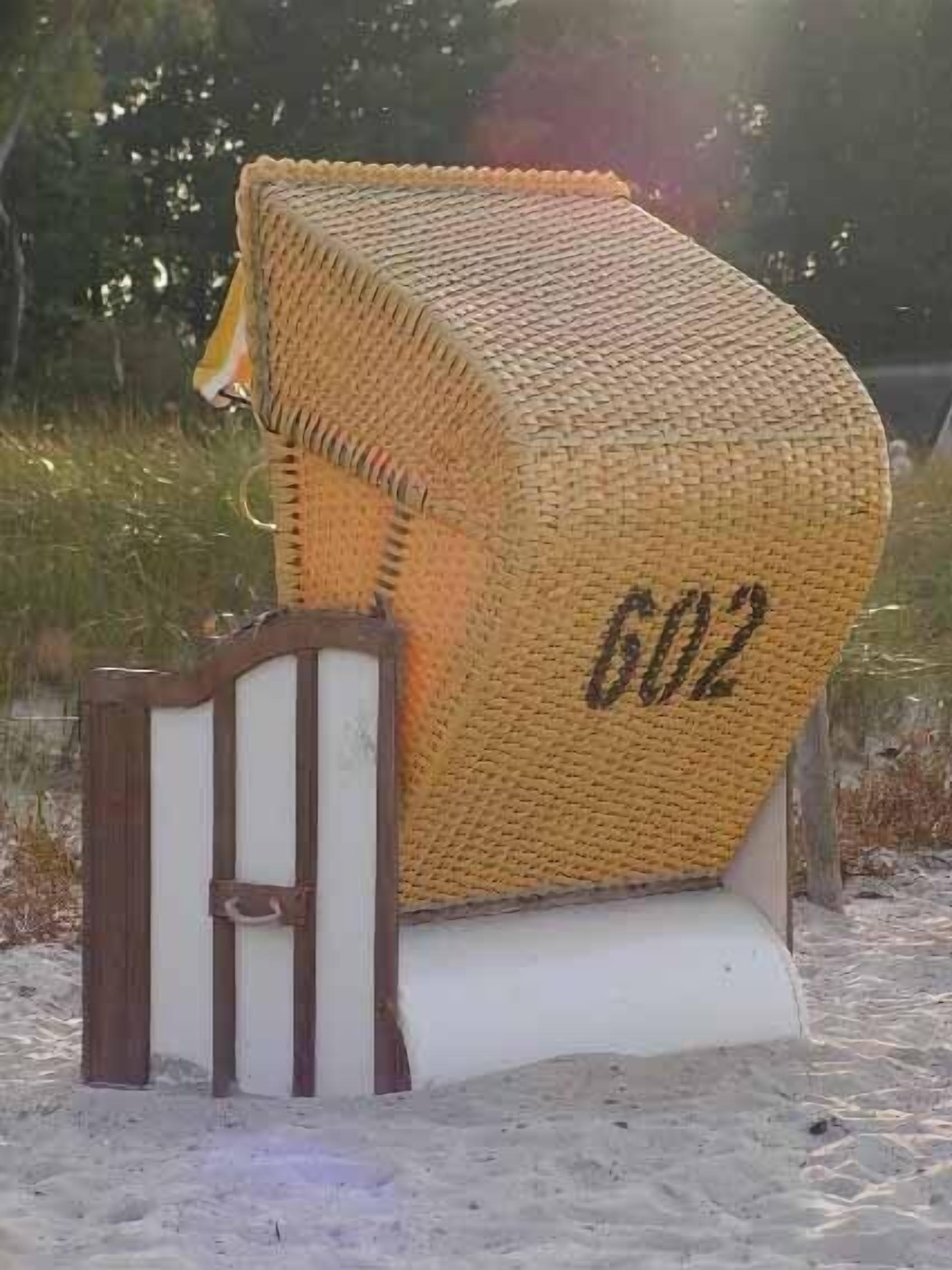 A beach hut with a woven roof and the number 602 on it.