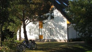 Ein weißes Haus mit schrägem Dach und einem Fahrrad davor.