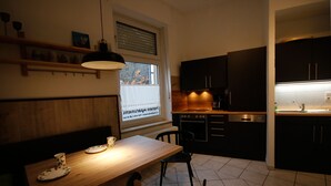 Une cuisine moderne avec des meubles en bois, une table à manger avec des chaises et une fenêtre avec des stores.