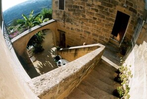 A stone staircase leading to a courtyard with a view of the surrounding landscape. - Romantic Farmhouse for up to 9 People with Pool and Sea View (Gozo)