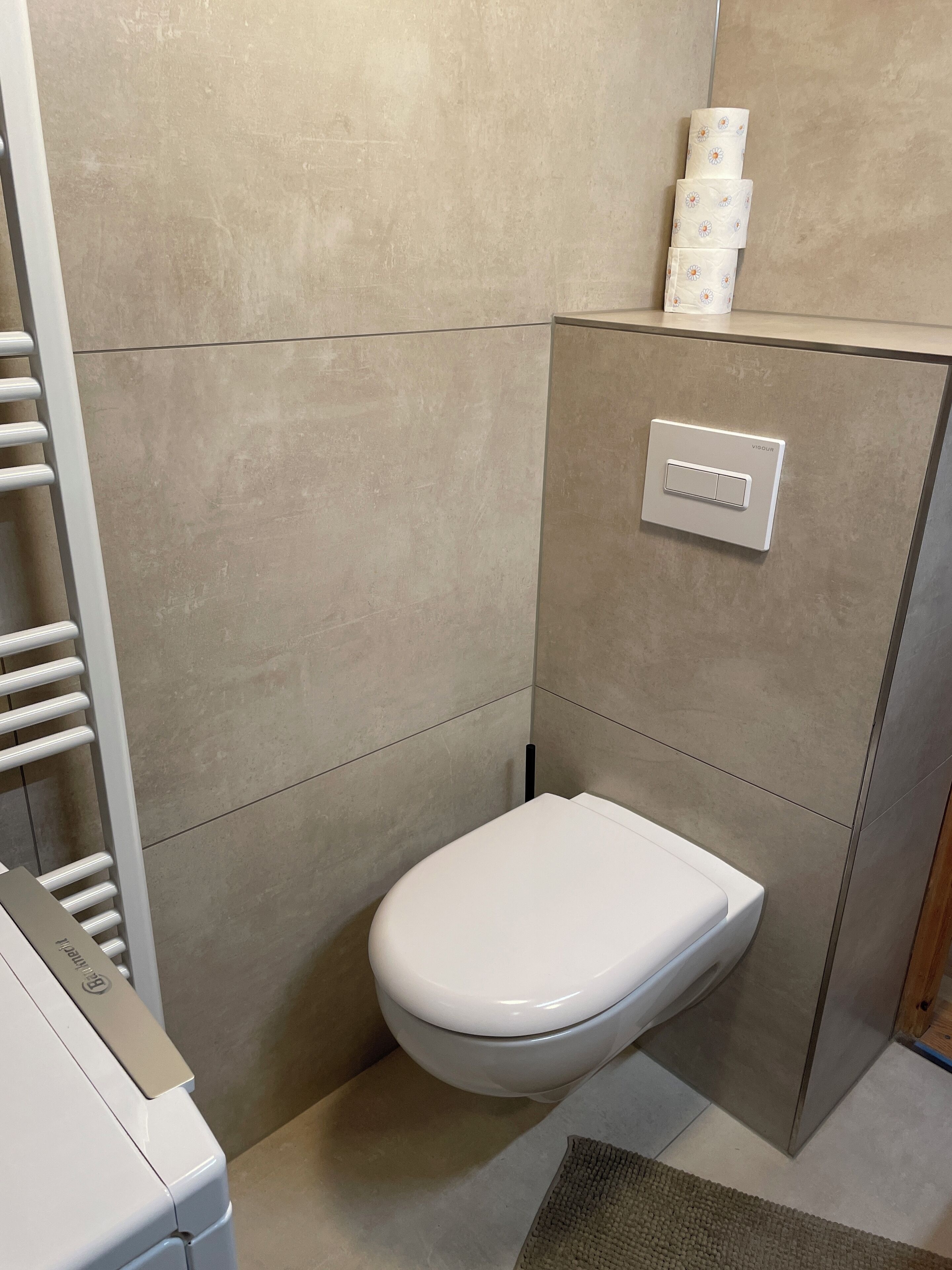 A modern bathroom with a toilet, a towel rack, and a toilet paper dispenser.