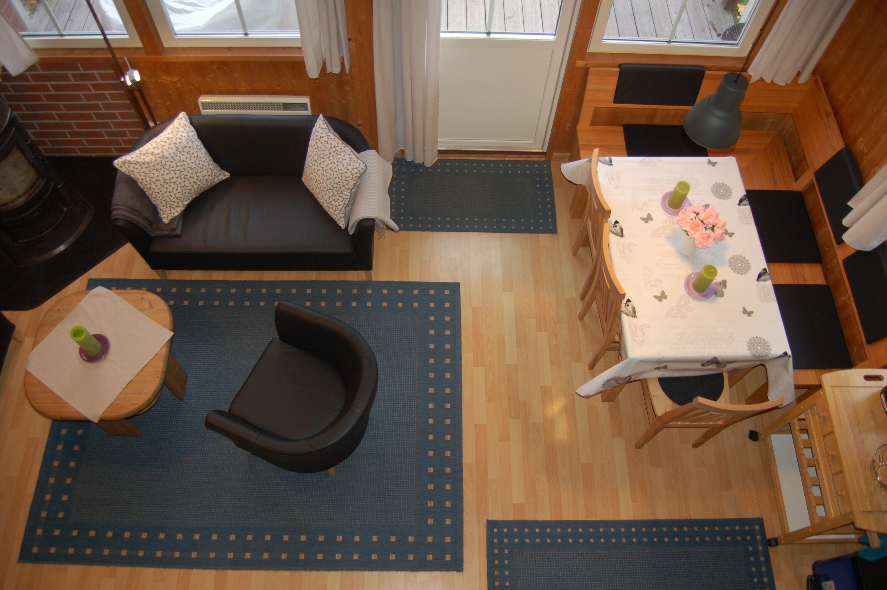 Une pièce chaleureuse avec un canapé, une table à manger et des chaises, une petite table avec une bougie, et une fenêtre avec des rideaux.