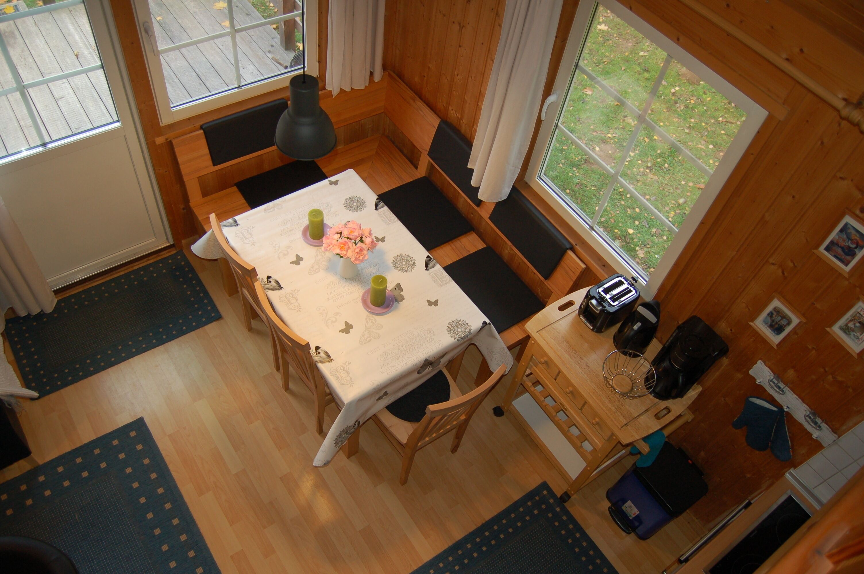 A cozy wooden cabin with a dining table set for four, a bench seating area, and a kitchen counter with appliances.