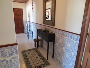 A hallway with a tiled floor, a wooden door, a small table with a lamp, and a mirror on the wall. - Convenient location at Europe's top beaches! (Lagos)