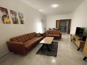 A living room with two brown sofas, a wooden coffee table, and a television on a wooden stand. - Convenient location at Europe's top beaches! (Lagos)