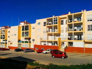 A multi-story apartment building with balconies, a parking lot, and a clear blue sky. - Convenient location at Europe's top beaches! (Lagos)