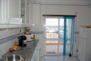 A kitchen with white cabinets, a coffee maker, a microwave, and a view of the city through a sliding glass door. - Convenient location at Europe's top beaches! (Lagos)
