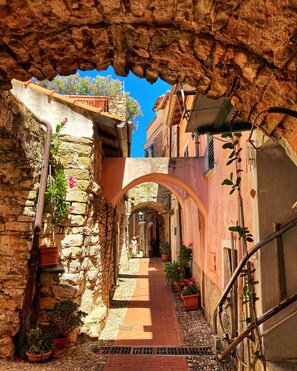 A narrow stone alleyway with a tiled pathway, flanked by buildings with stone walls and potted plants. - Holiday house with sea view and sun terrace, 4 km to beach (Cipressa)