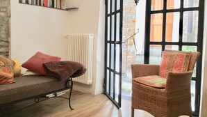 A cozy room with a wicker chair, a sofa with cushions, a bookshelf, and a large window with a view of the outside. - Holiday house with sea view and sun terrace, 4 km to beach (Cipressa)