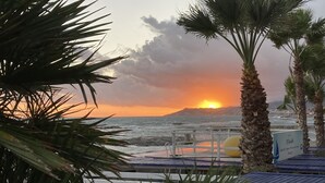 A sunset view with palm trees and a beach. - Holiday house with sea view and sun terrace, 4 km to beach (Cipressa)
