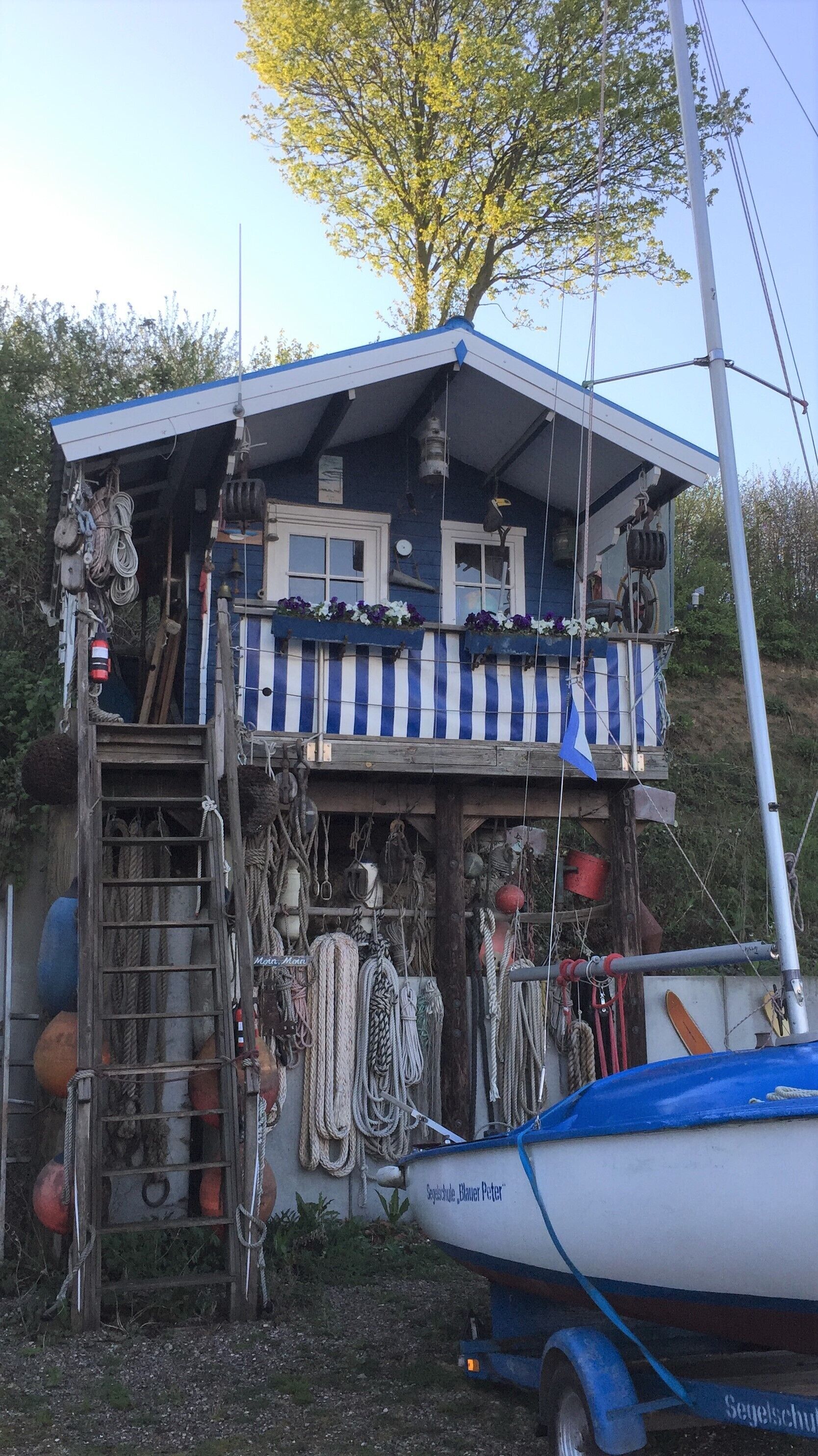 A small wooden structure with a balcony, surrounded by various ropes and equipment.