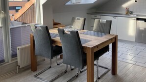 A modern kitchen with white cabinets, a dining area with a wooden table and grey chairs, and a skylight above the dining area. - TOP HOLIDAY APARTMENT 65 SQM WITH 2 BEDROOMS, WLAN, balcony (Grömitz)