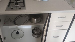 A kitchenette with a gas stove, a microwave, and various kitchenware including pots and a kettle.
