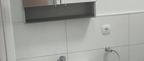 A bathroom with a white sink, a mirror above it, and a towel rack.