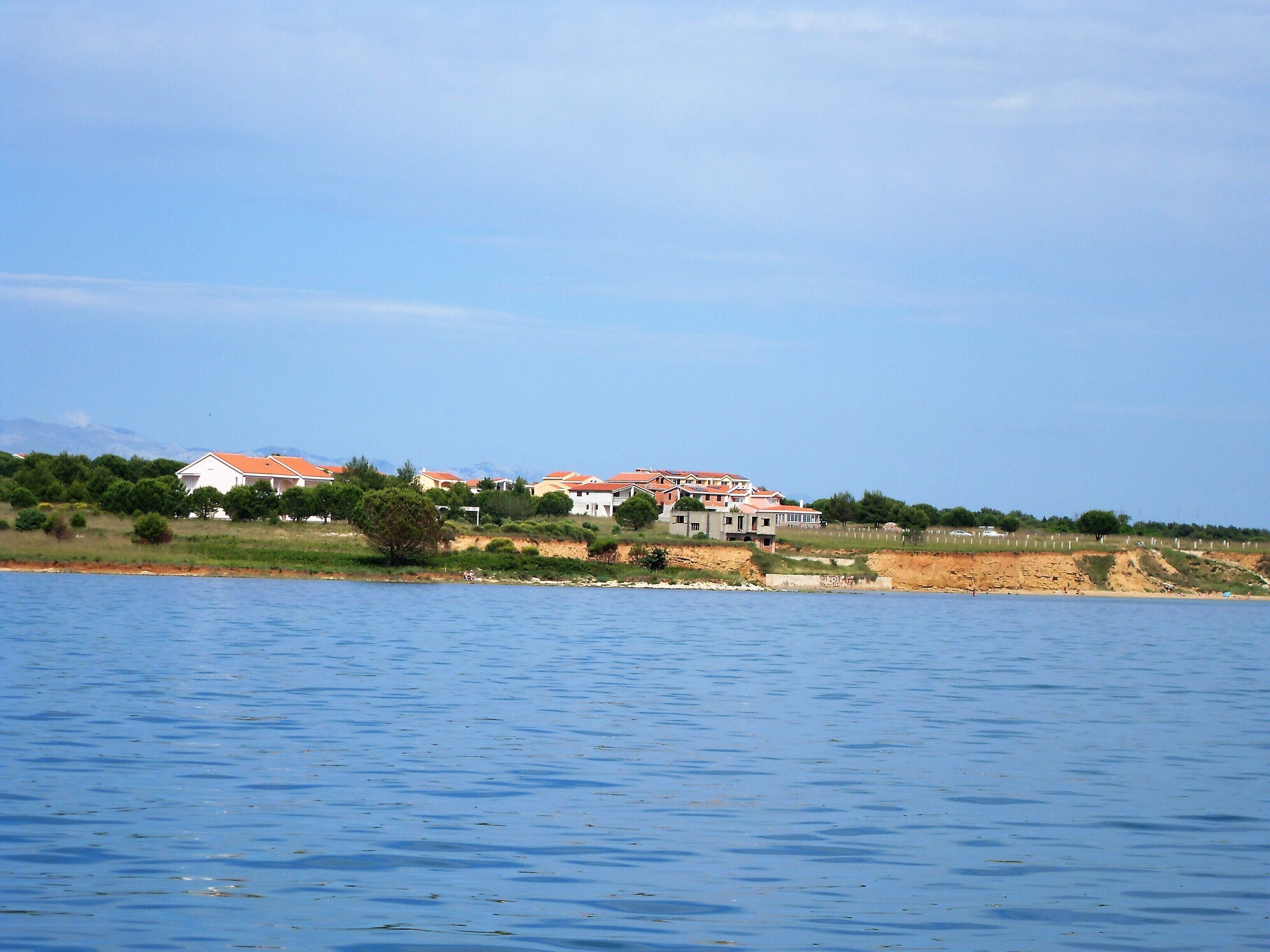 A coastal property with multiple buildings, a beach, and a clear view of the sea.