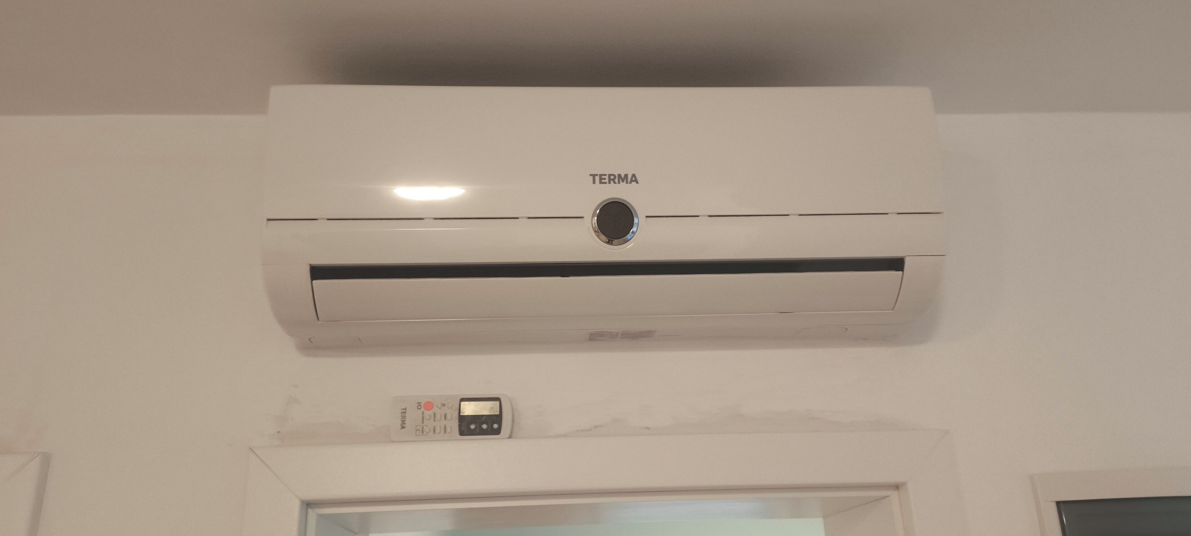 En hvid aircondition-enhed med et kontrolpanel nedenunder.