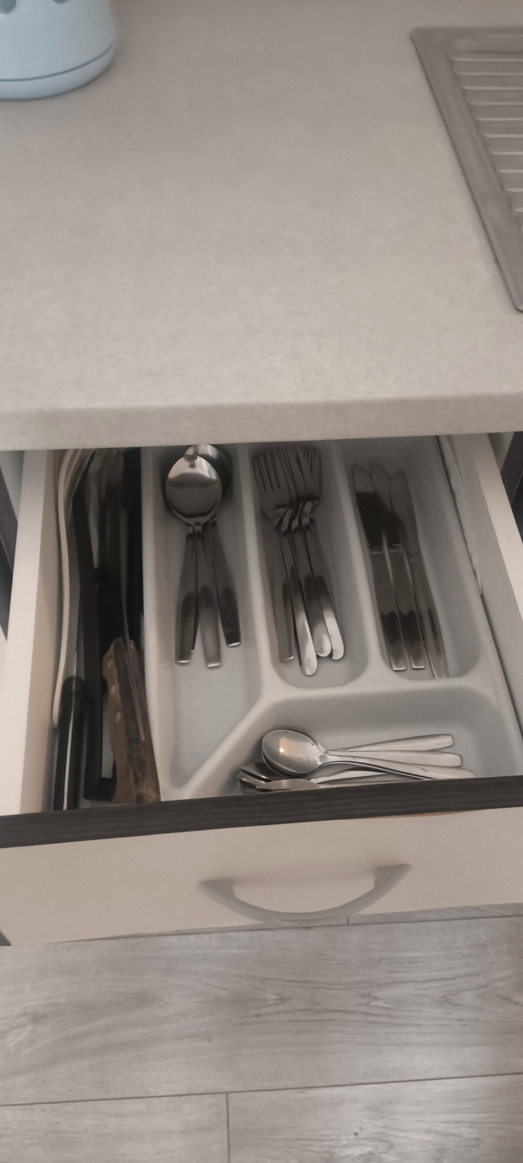 A drawer with neatly organized utensils including forks, knives, and spoons.