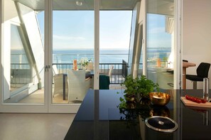 Quarto moderno com porta de vidro que dá para uma varanda com vista para o mar.