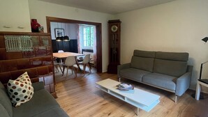 A living room with a sofa, a coffee table, and a dining area with chairs and a table.
