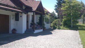 Ein Gebäude mit Ziegeldach, einem Pflastervorplatz und Blumentöpfen.