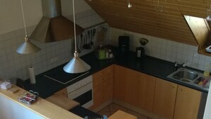 Eine Küche mit einer zentralen Kochinsel, Holzschränken, einem Herd und hängenden Pendelleuchten.