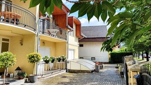 A courtyard with a cobblestone path, potted plants, a covered seating area, and a building with a balcony. - New, modern apartments, bright, friendly and clean! Many regular guests.  (Hévíz)