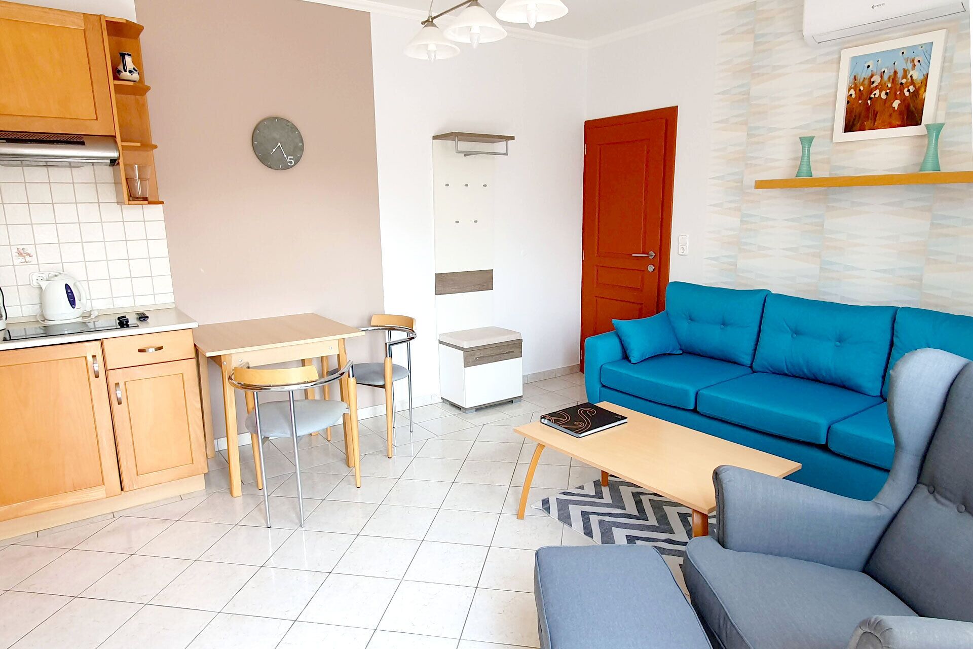 A compact living space with a kitchenette, a dining area, a sofa, and a small table.