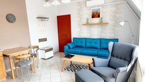 A modern living room with a blue sofa, a grey armchair, a wooden table, and a small white cabinet. - New, modern apartments, bright, friendly and clean! Many regular guests.  (Hévíz)