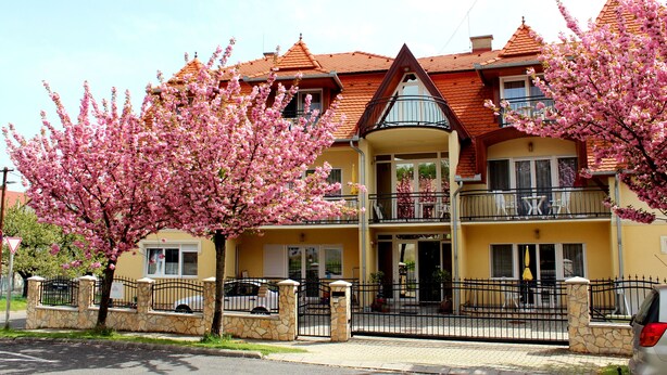 A two-story building with a yellow facade and red-tiled roof, featuring balconies and a gated entrance. - New, modern apartments, bright, friendly and clean! Many regular guests.  (Hévíz)