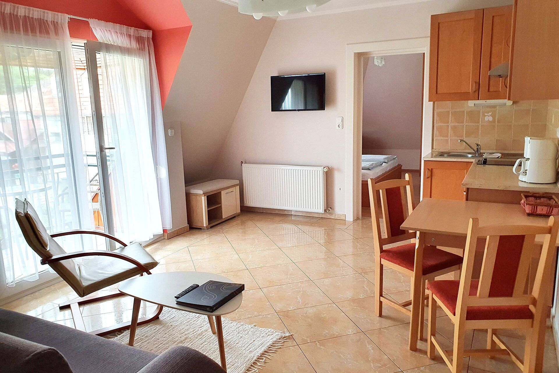 Ein kompakter Wohnraum mit Küchenzeile, Essbereich und einer Sitzecke mit Blick ins Freie.