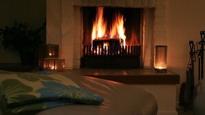 Una chimenea encendida, una vela y una planta en una habitación.