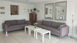 A living room with two grey sofas, a white coffee table, and a wooden cabinet. - Haus Lena - Holiday near the Baltic Sea including free Wi-Fi (V-DSL) (Pansdorf)