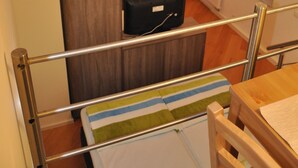 Une petite pièce comprenant un lit, une petite table et un meuble en bois.