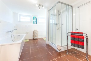 A modern bathroom with a glass-enclosed shower, a freestanding bathtub, and a towel rack with a striped towel.
