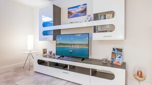 A modern living room with a flat-screen TV, built-in shelves, a small table, and a wine glass.