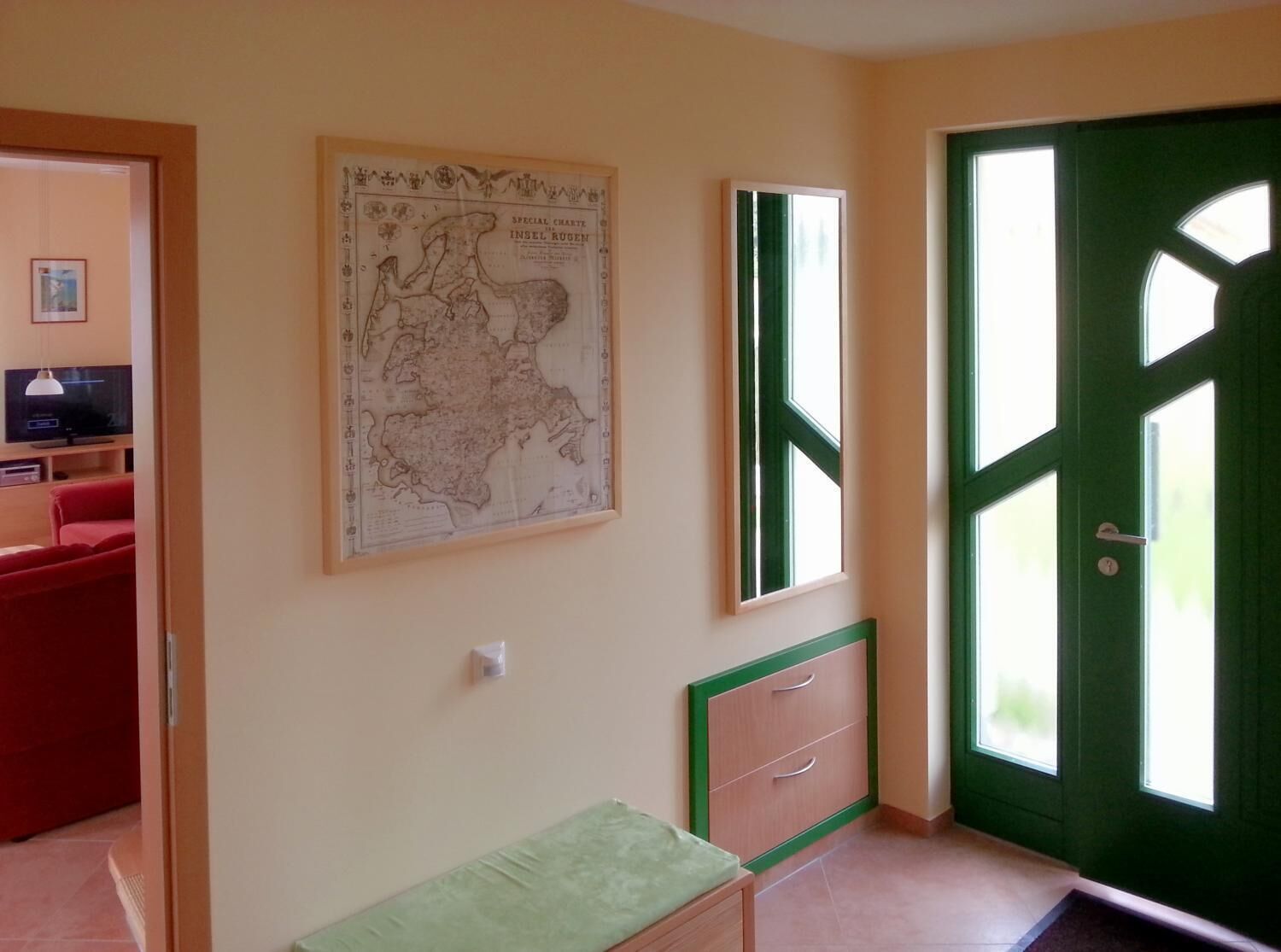 A room with a map on the wall, a green door, and a small desk with drawers.