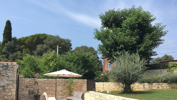 Una piscina con paredes de piedra, sillas de descanso y una sombrilla.