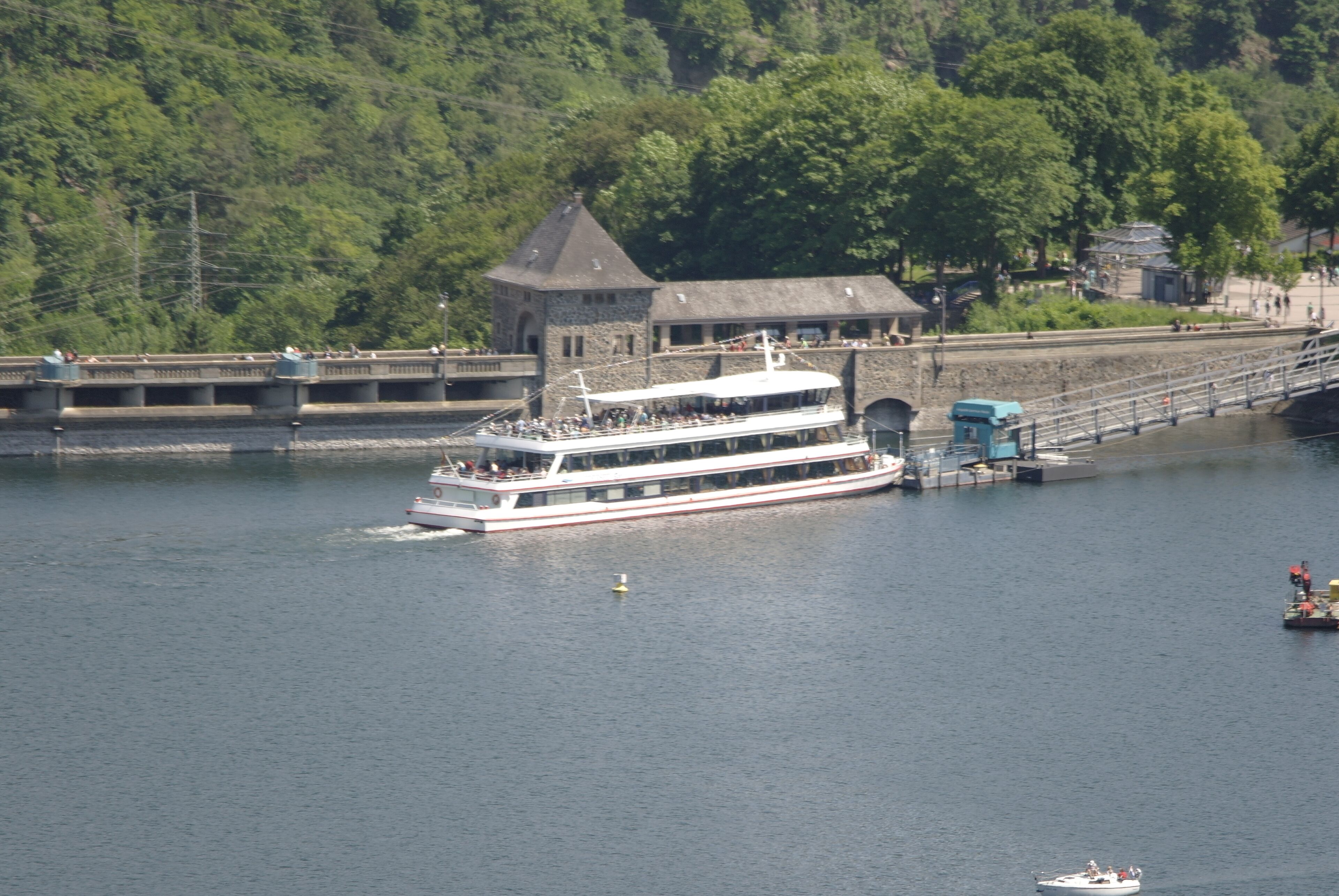 Un grand bateau fluvial était amarré à un quai, avec un bâtiment en pierre en arrière-plan.