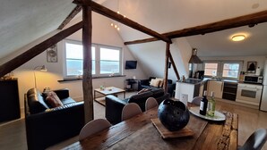 A loft-style living space with a dining area, a kitchen, and a large window offering a view. - Nice apartment with beautiful lake view and large garden (Waldeck)