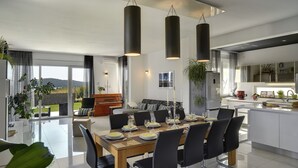 Un espace repas moderne avec une grande table dressée pour six personnes, entourée de chaises noires.