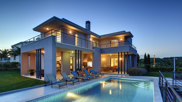Une maison moderne à deux étages, dotée d’une piscine, d’un espace de détente extérieur et d’une pelouse bien entretenue.