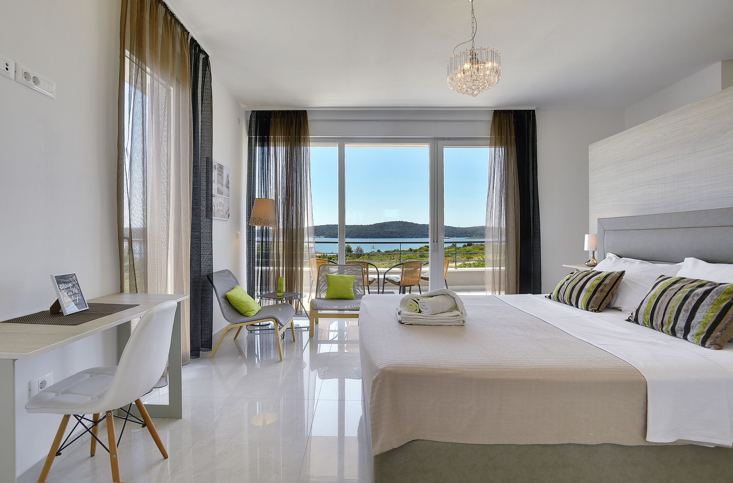 Una habitación de hotel moderna con una cama grande, un escritorio, una silla y vistas al mar.