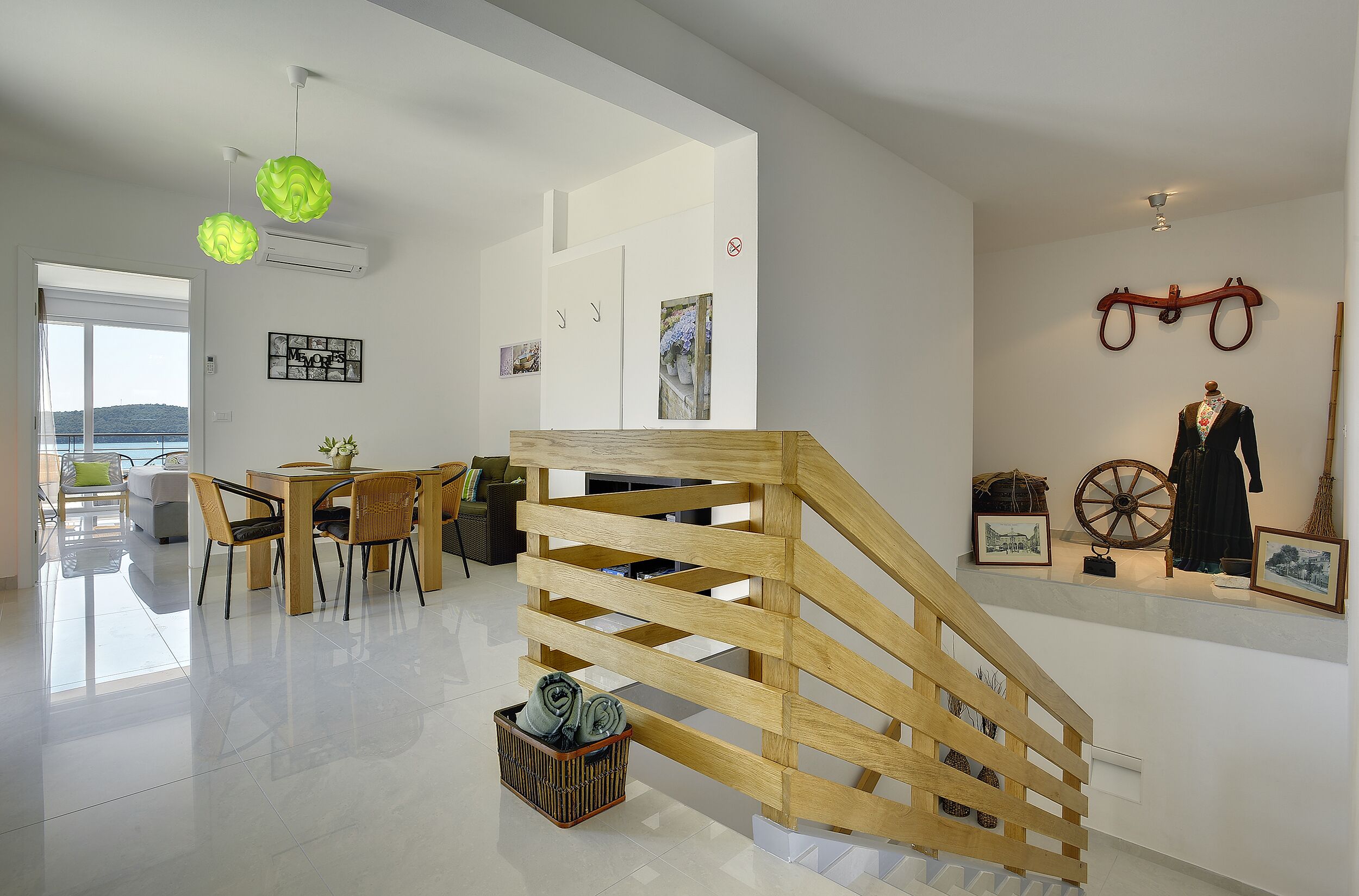 A modern interior with a wooden staircase, a dining area, and a view through a glass door.