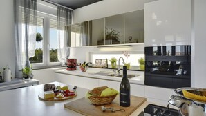 Une cuisine moderne dotée d’un îlot central, d’un four encastré et d’une grande fenêtre.